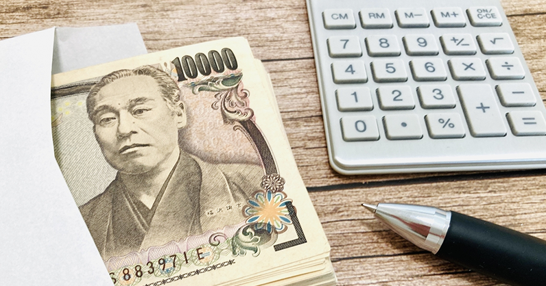 1万円札の束と電卓とペン